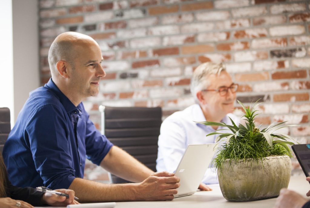 Twee mannen aan tafel met laptops en planten