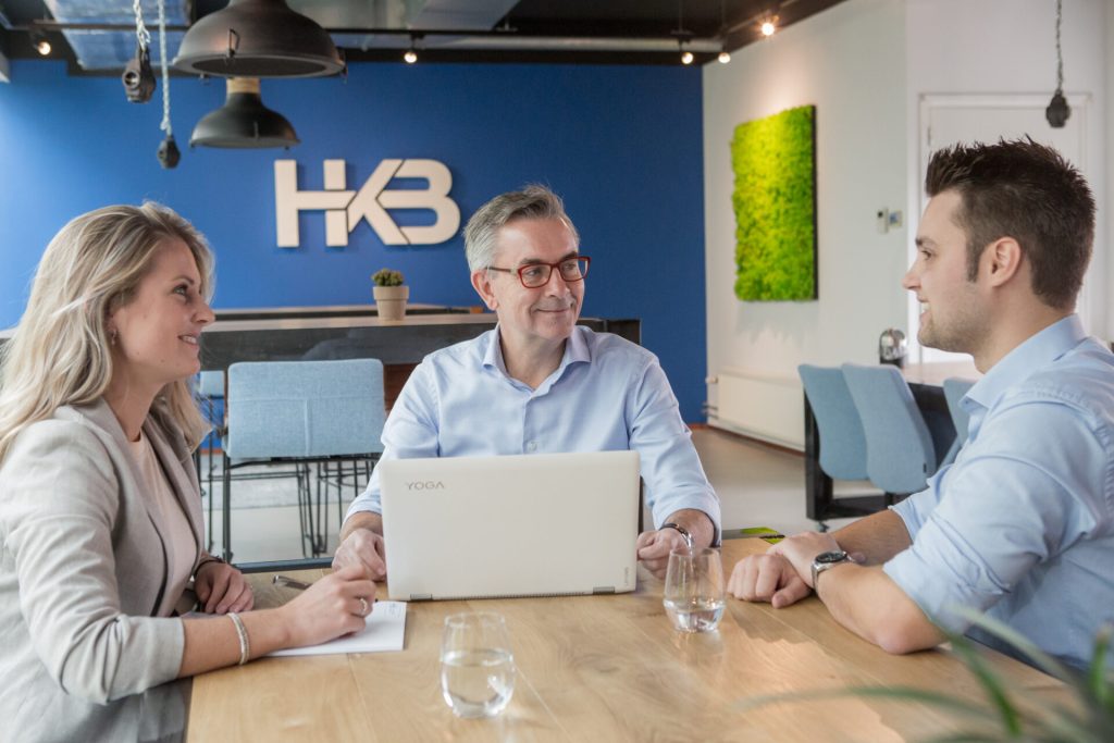 Collega's in bespreking bij vergadertafel met laptop.