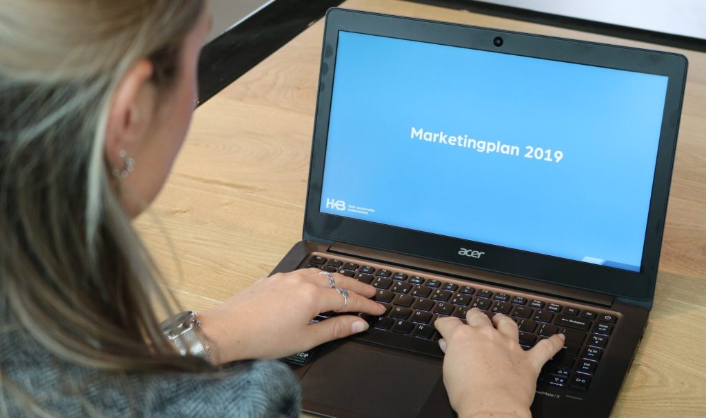 Persoon werkt aan marketingplan op laptop.