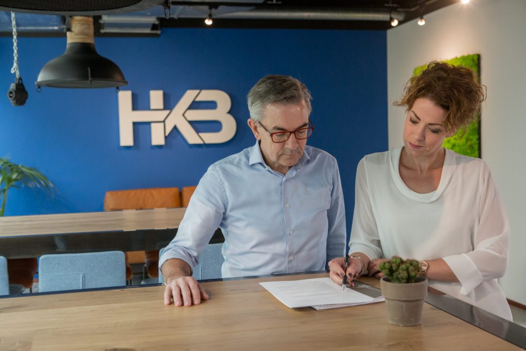 Twee mensen bespreken documenten aan een tafel.