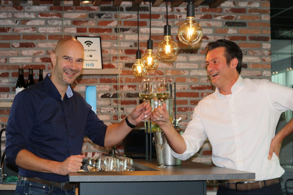 Twee mannen proosten met wijnglazen in een bar.