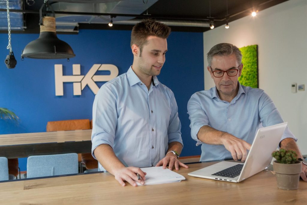 Twee mannen werken samen op kantoor met laptop.