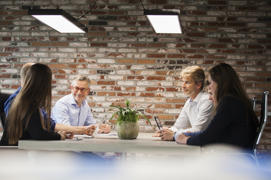 Mensen vergaderen aan tafel met plantenpot.