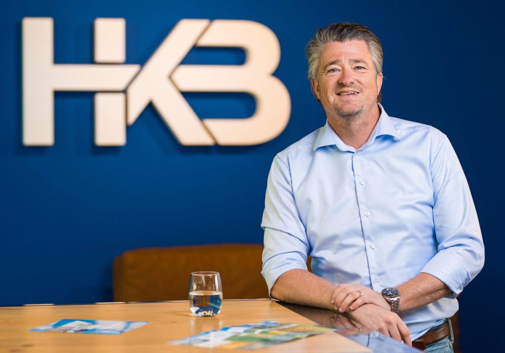 Man poseert bij tafel in kantooromgeving.