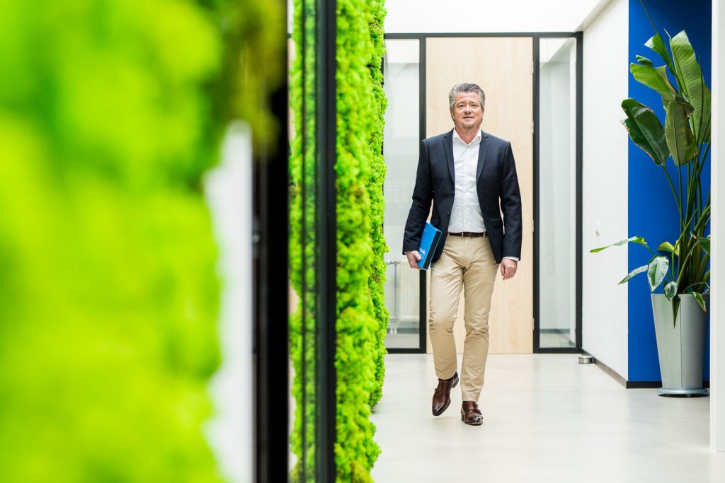 Man loopt door moderne kantoorhal met planten