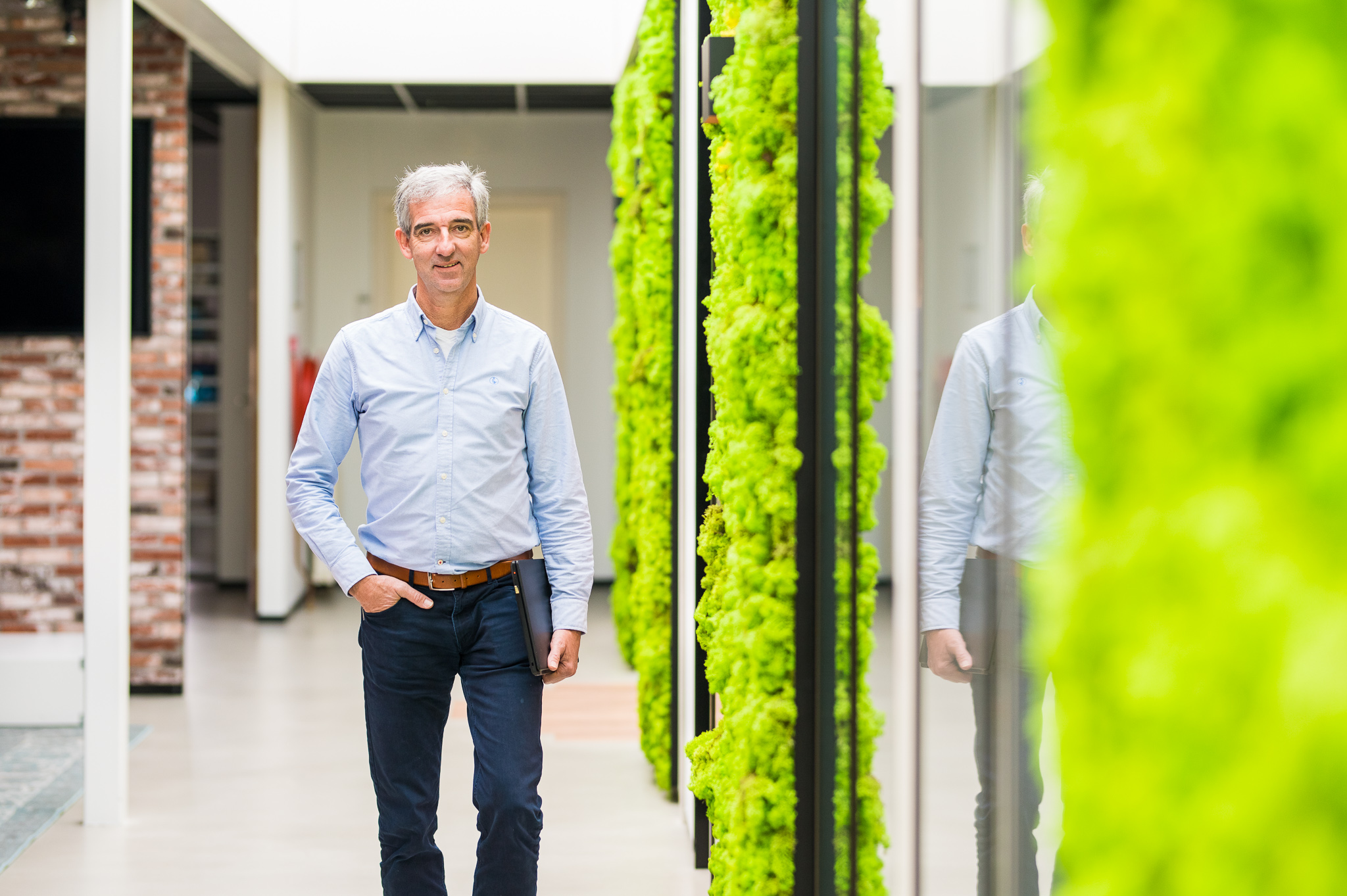 Man loopt door kantoor met groene muur.
