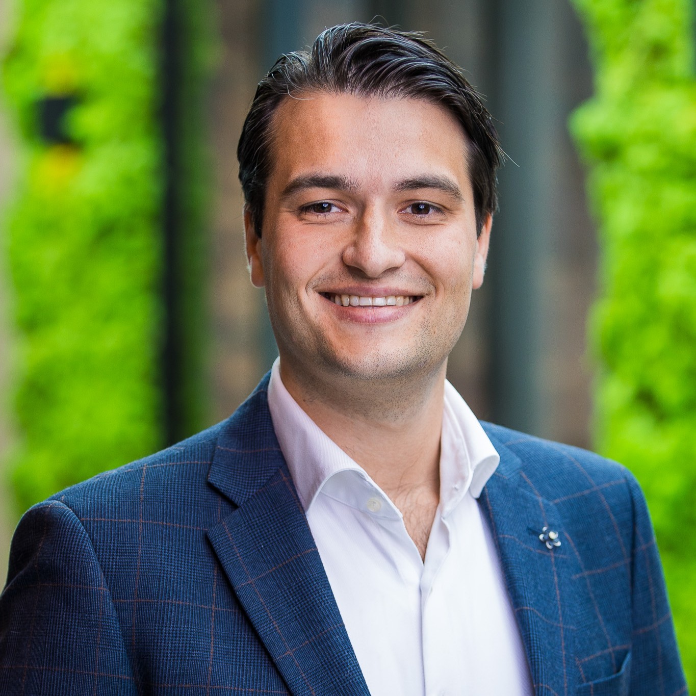 Man in formeel blauw pak, lachend buiten