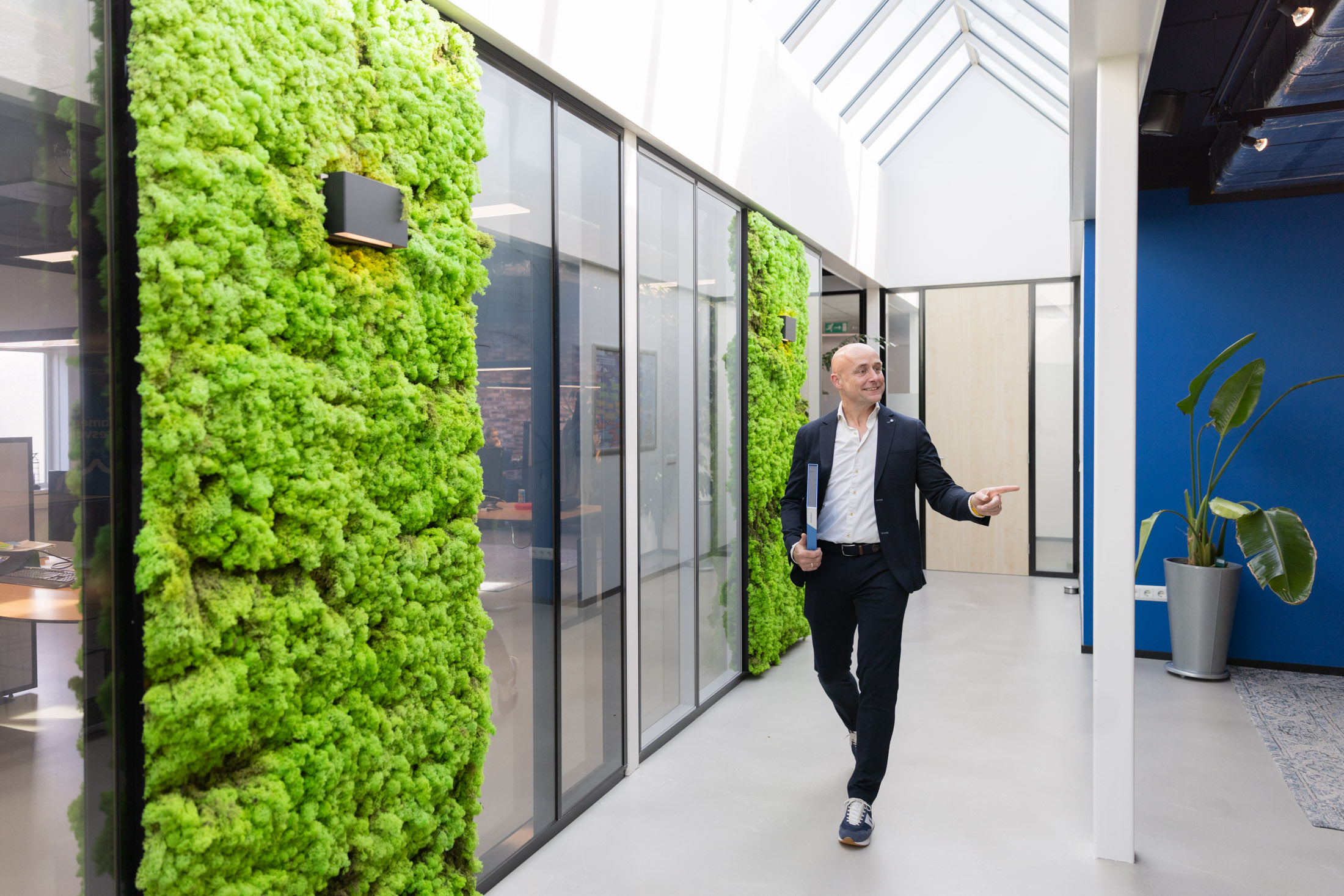 Man loopt in kantoor met groene moswand.