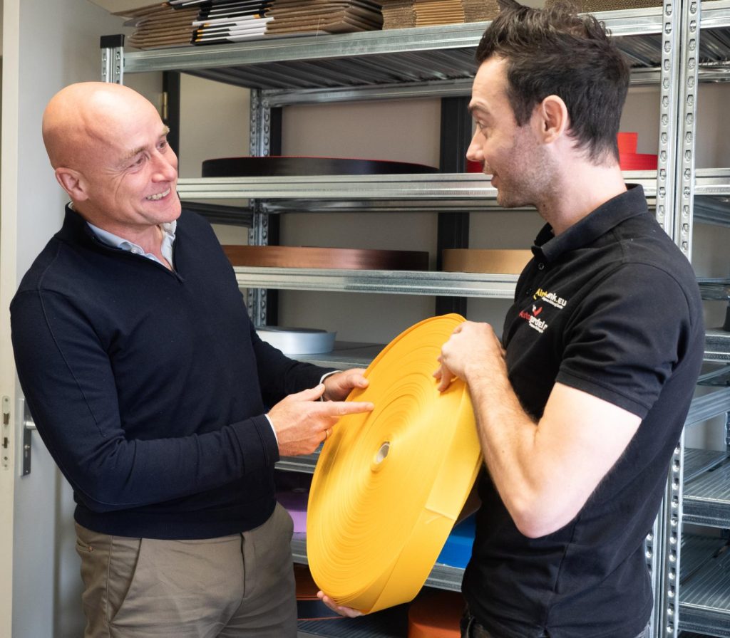 Twee mannen bespreken grote gele rol tape.