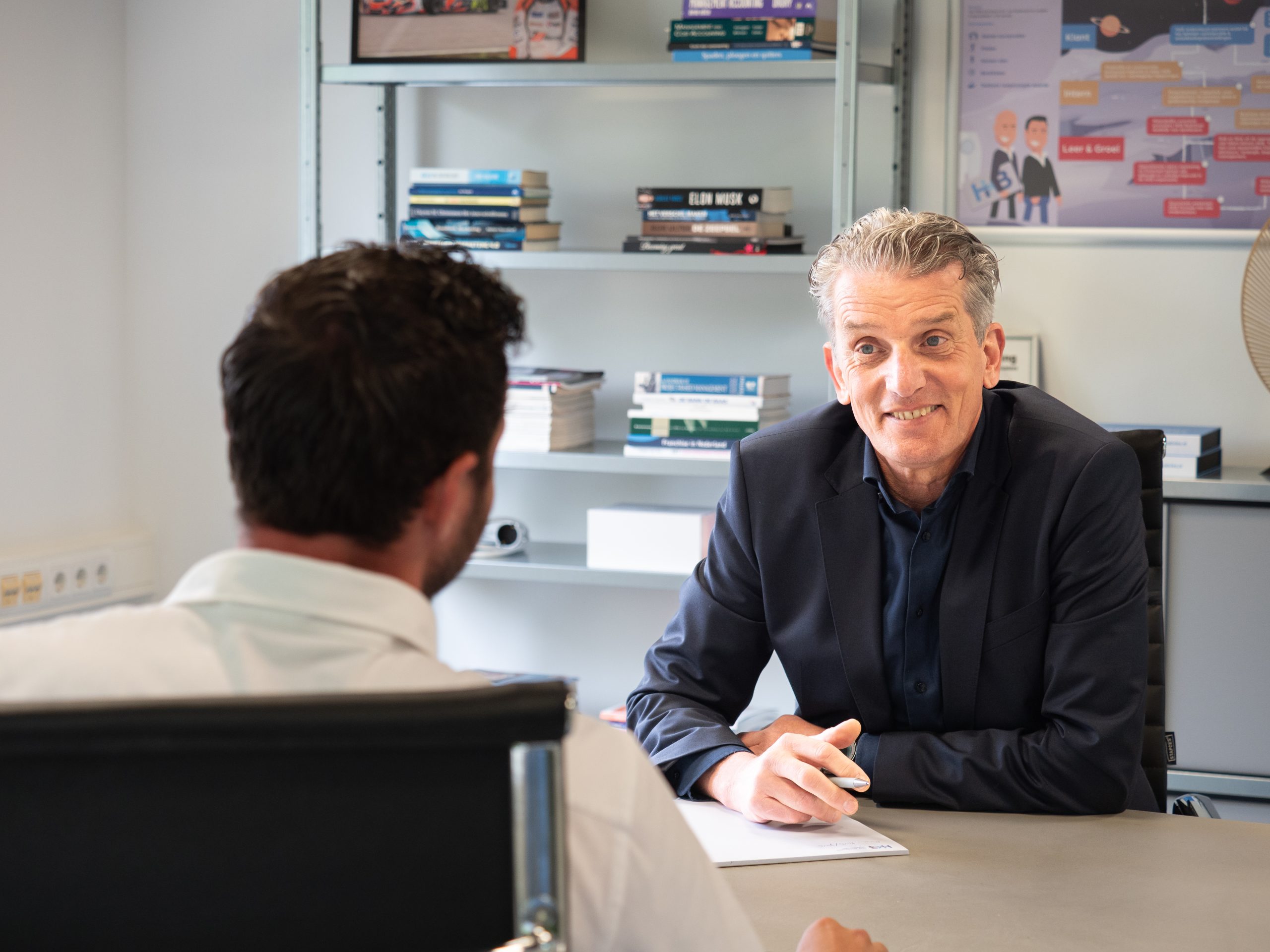 Twee mannen praten aan tafel in kantoor.
