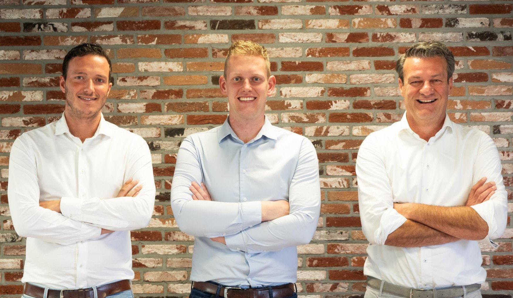 Drie mannen voor een bakstenen muur.