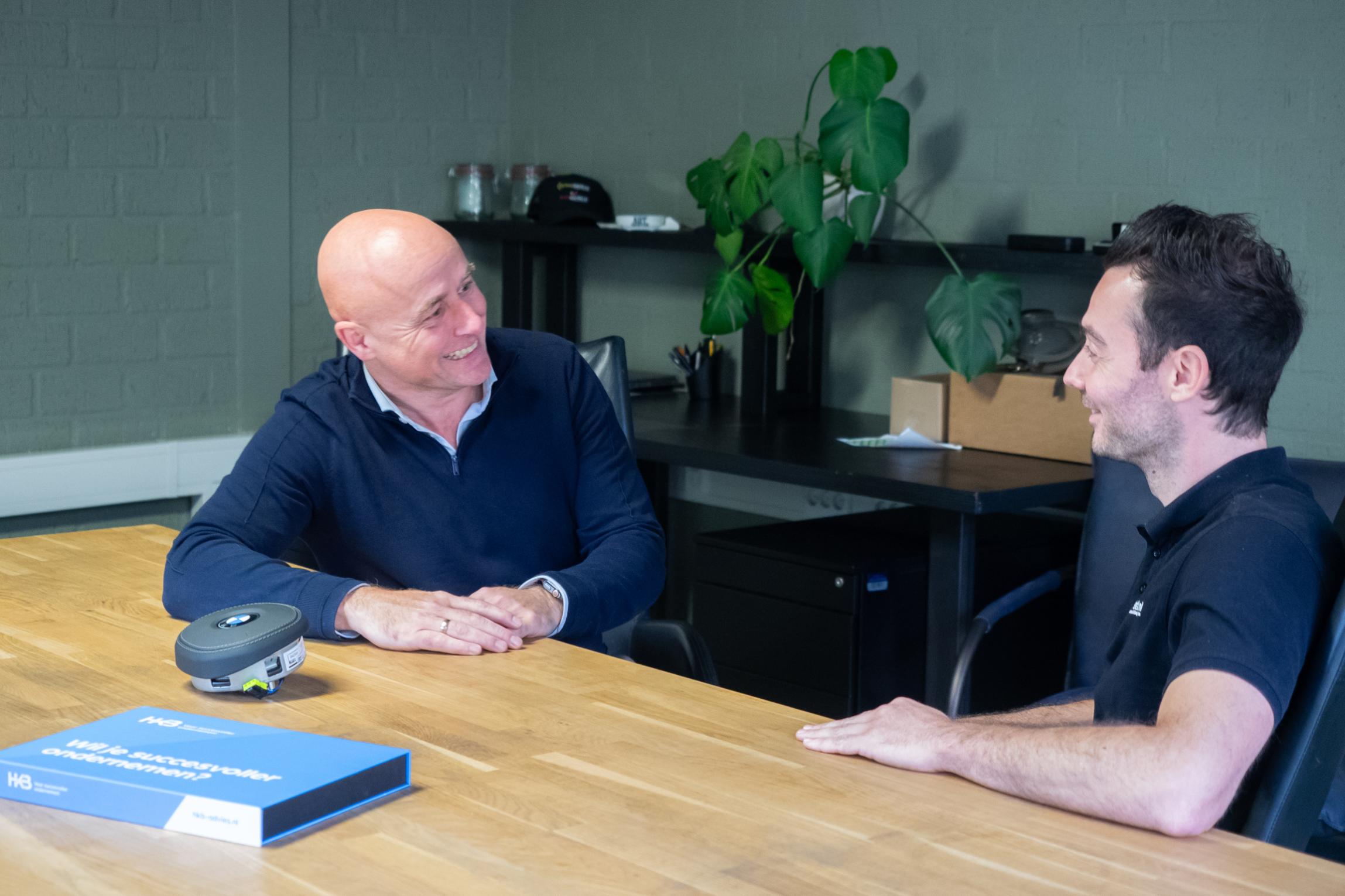 Twee mannen praten en glimlachen aan een tafel