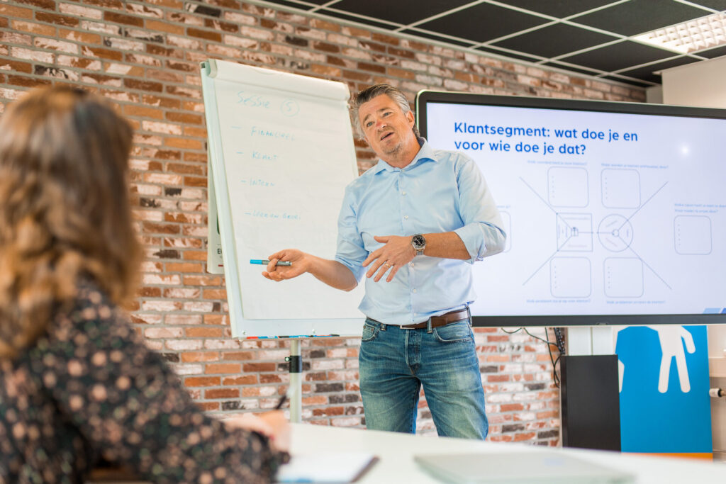 Man geeft presentatie voor medewerker bij flipover.