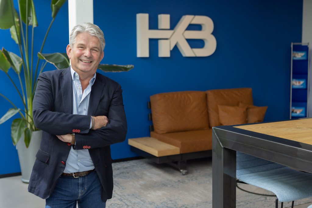 Man poseert in modern kantoor met blauwe muur.