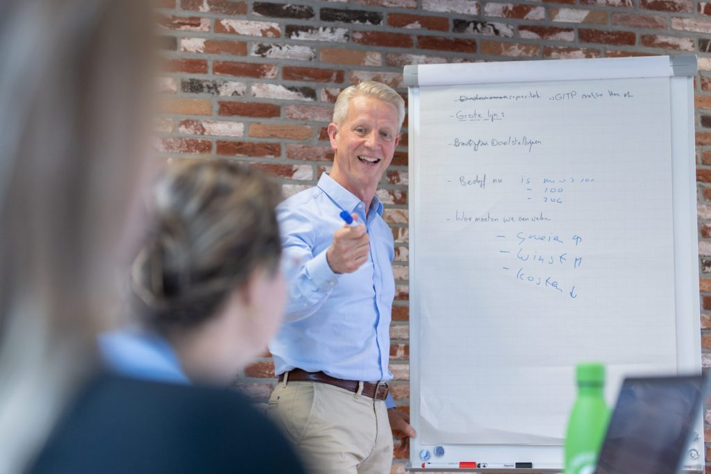Man geeft presentatie met whiteboard in vergaderruimte.