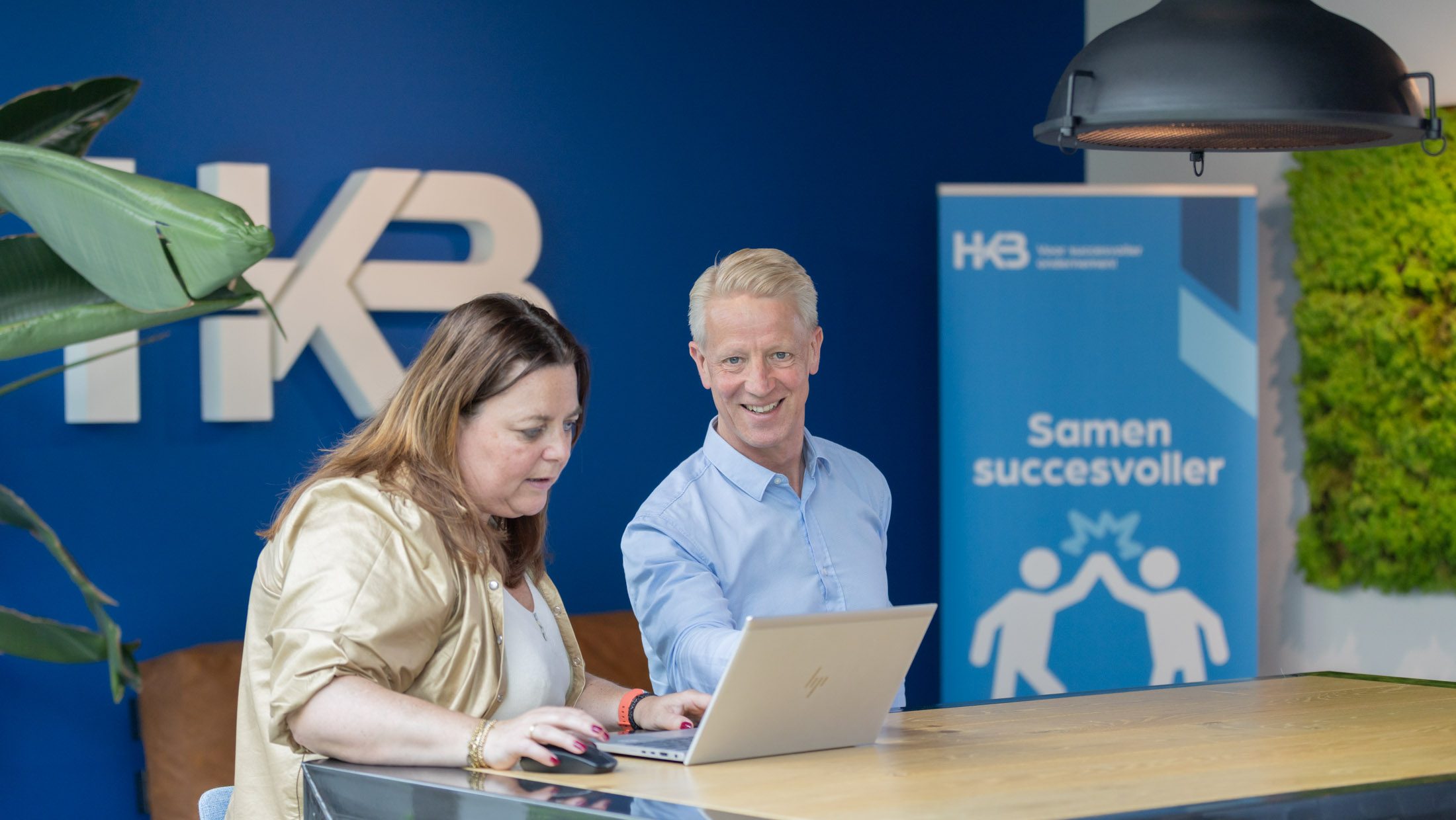 Twee mensen werken samen aan een laptop bij HKB.