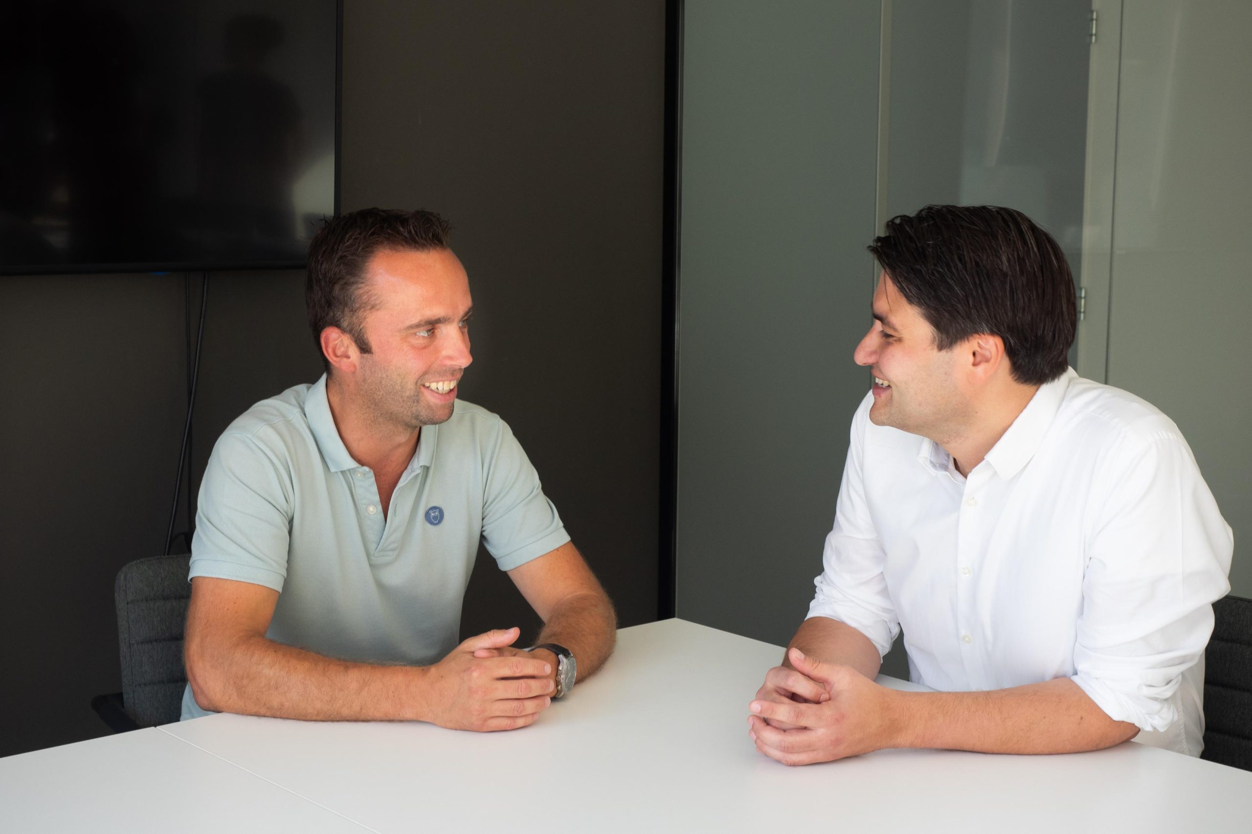 Twee mannen in gesprek aan een tafel.