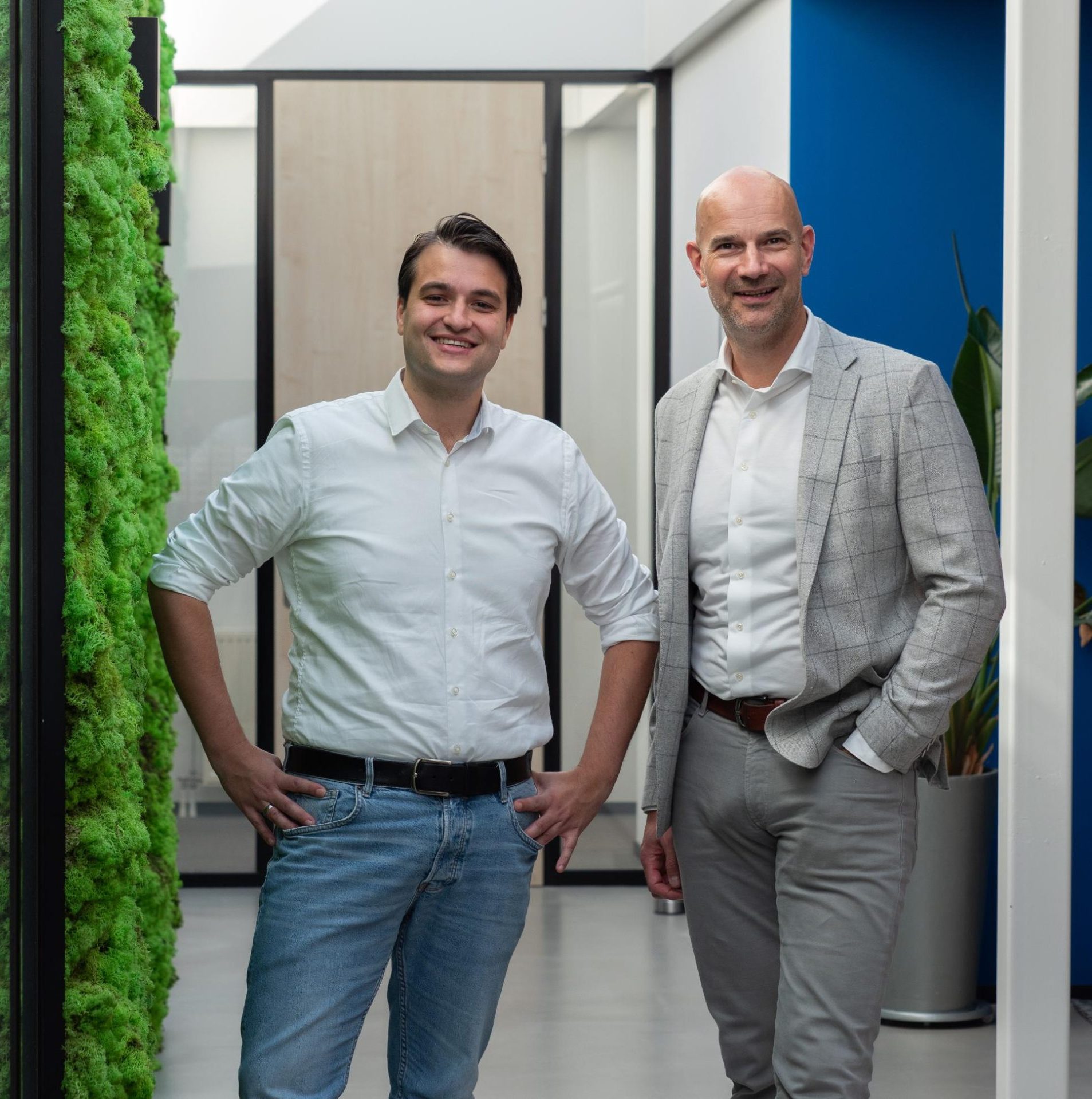 Twee mannen in kantoor bij groene muur.