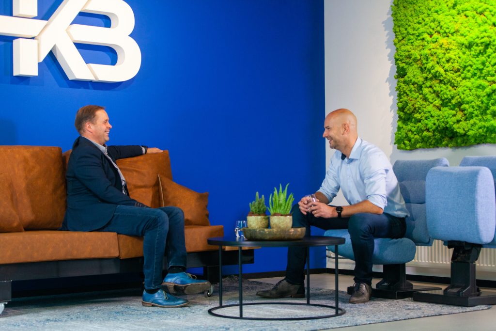 Twee mannen praten in kantooromgeving met planten.