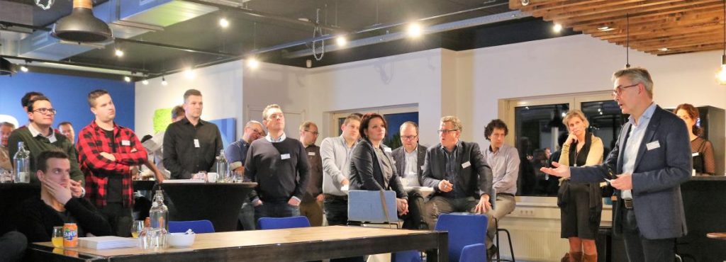 Zakelijke presentatie met luisterend publiek in kantoorruimte.