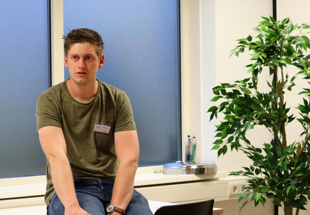 Persoon zittend op tafel voor raam met plant.