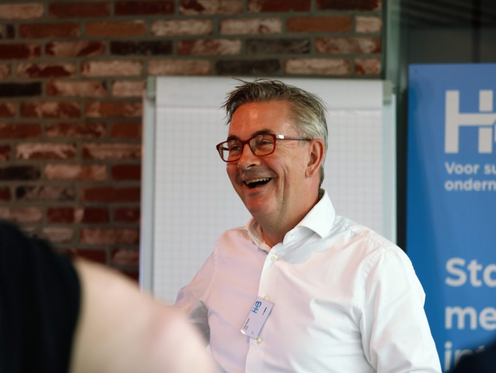 Lachende man in witte blouse bij conferentie