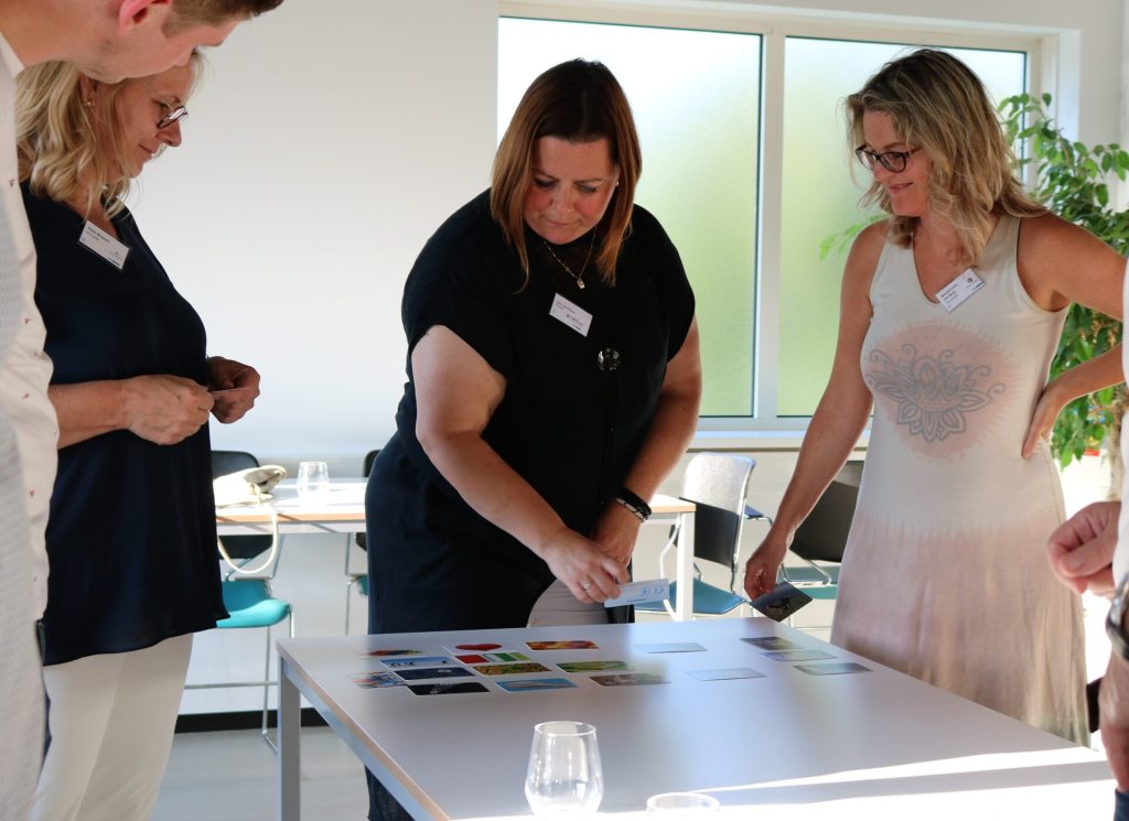 Groep mensen bekijkt kaarten op tafel.