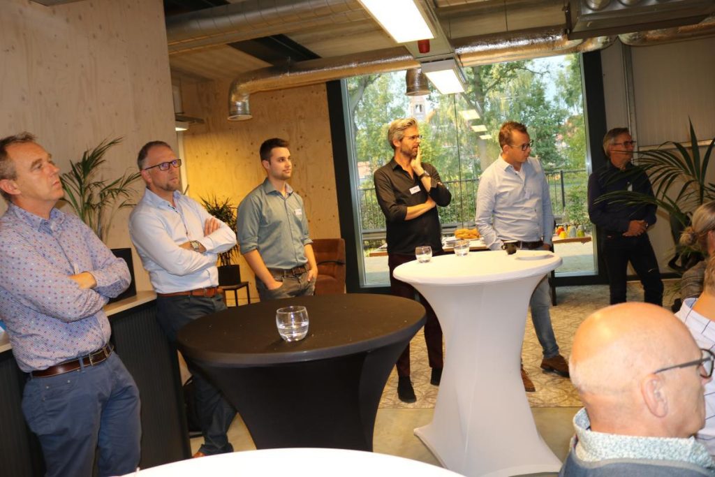 Mensen luisteren tijdens een bijeenkomst in kantoorruimte.