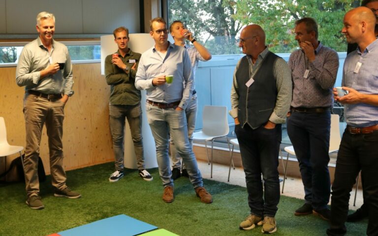 Groep mannen in gesprek op kantoor binnen.