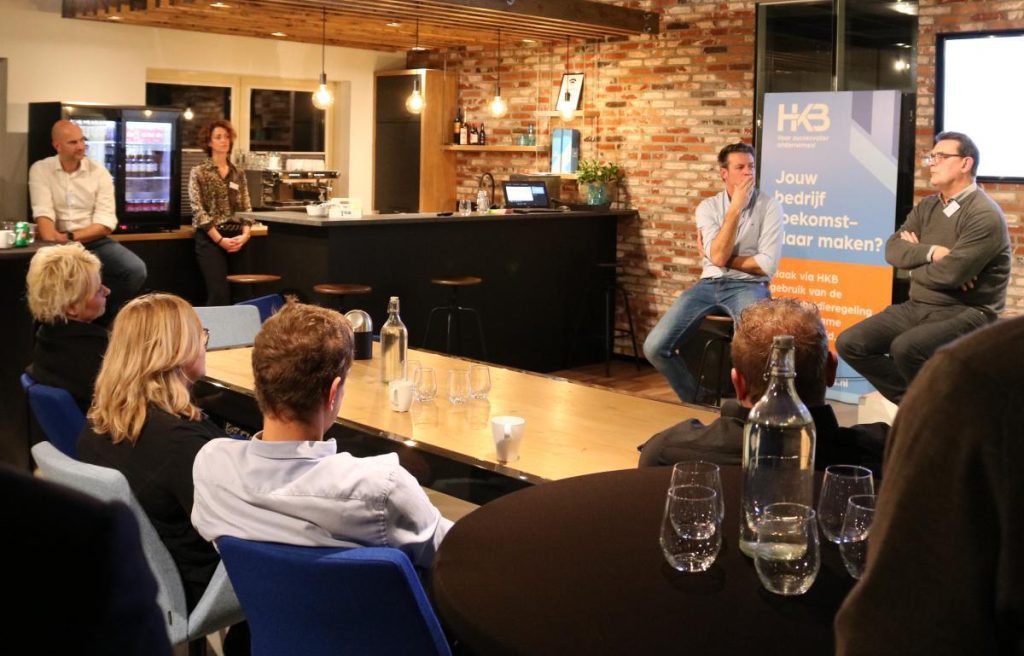 Discussieavond in kantoor met twee sprekers en publiek.