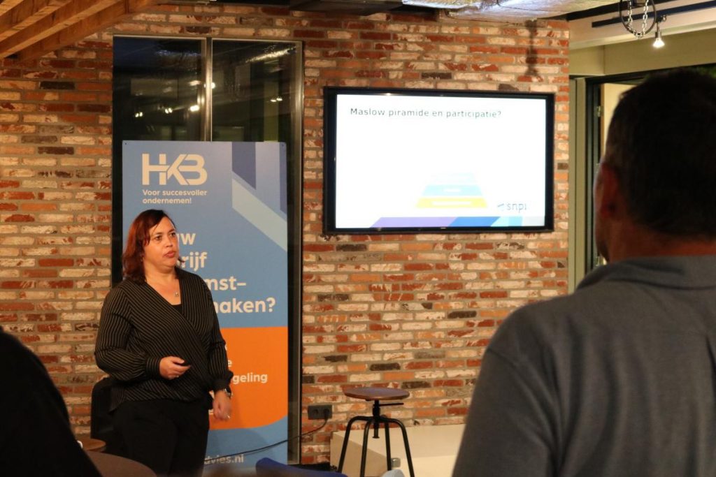 Vrouw presenteert over Maslow's piramide en participatie