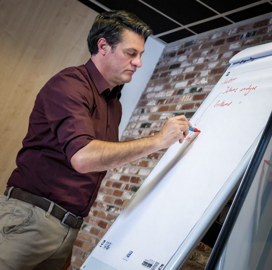 Man schrijft op flip-over tijdens vergadering.