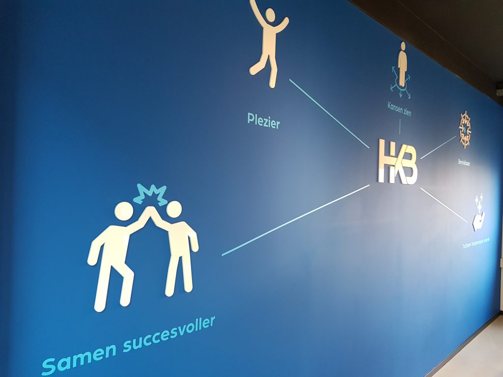 Wand met bedrijfswaarden en HKB-logo.