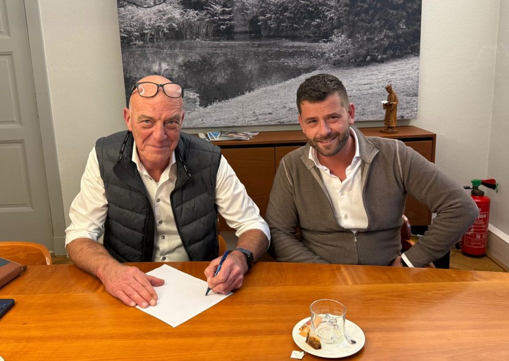Twee mannen aan een tafel met documenten.