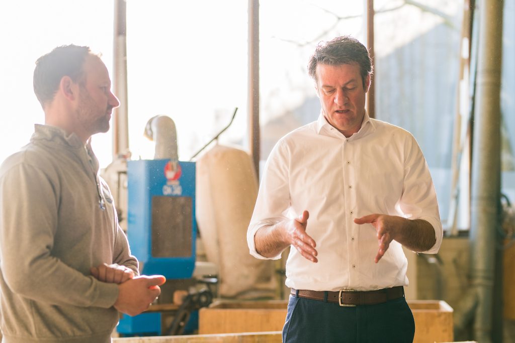 Twee mannen in gesprek bij werkplaats.